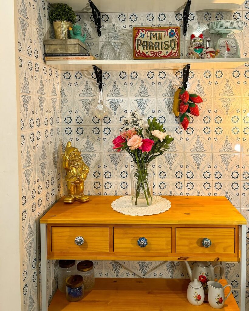 Cantinho com balcão de madeira, guardanapo de crochê e vaso de flores, azulejos com flores azuis e enfeites