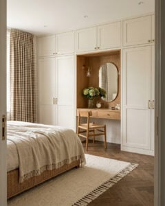 Quarto em cores neutras com guarda-roupa claro e penteadeira embutida em tons amadeirados