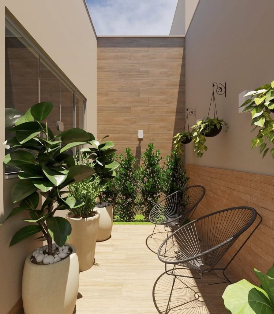 Corredor com plantas penduradas, vasos grandes de cerâmica com folhagens e cadeiras aramadas