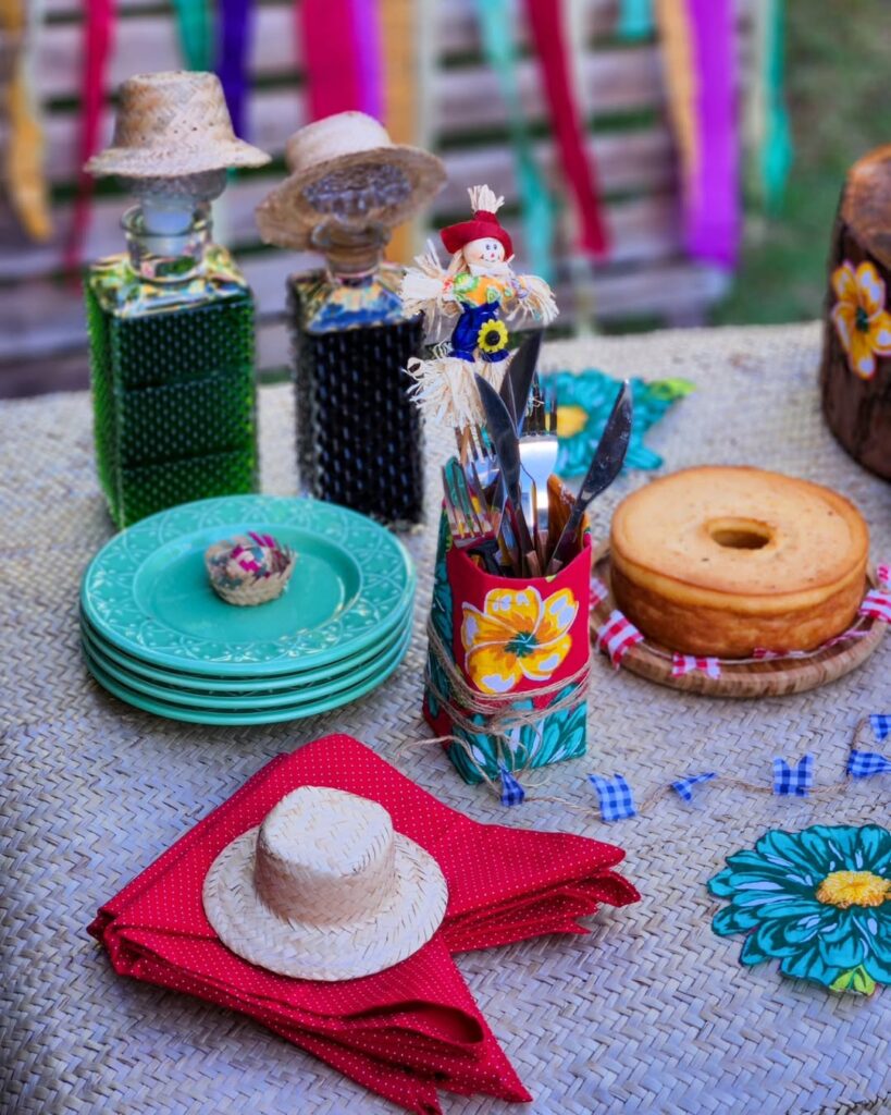 Mesa de São João com guardanapos dobrados em formato de baideirinha, suporte com talheres e espantalho