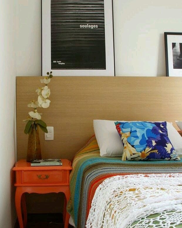 Quarto com mesa de cabeceira laranja com detalhes ornamentados
