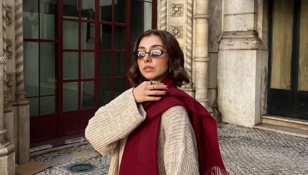 Mulher jovem de pele clara usando cachecol feminino vermelho e suéter marrom claro
