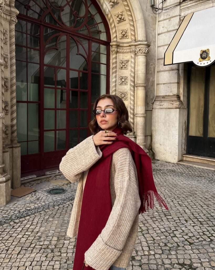 Mulher jovem de pele clara usando cachecol feminino vermelho e suéter marrom claro