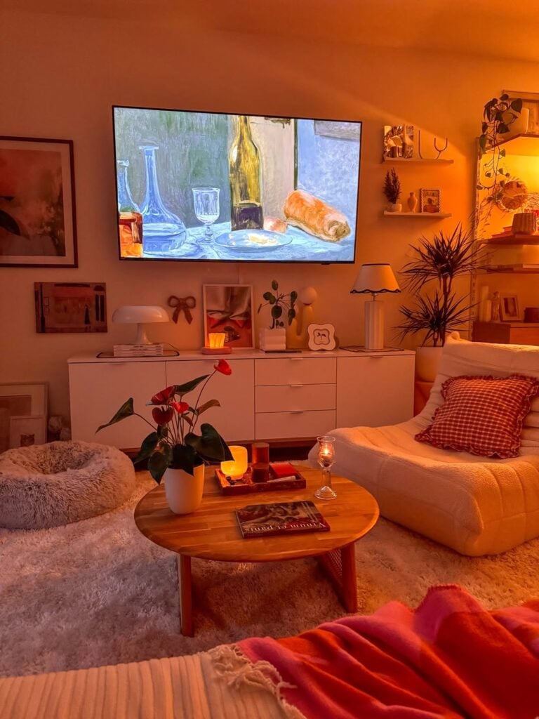 Sala de estar aconchegante com luzes amarelas, mesa de centro de madeira e buffet branco