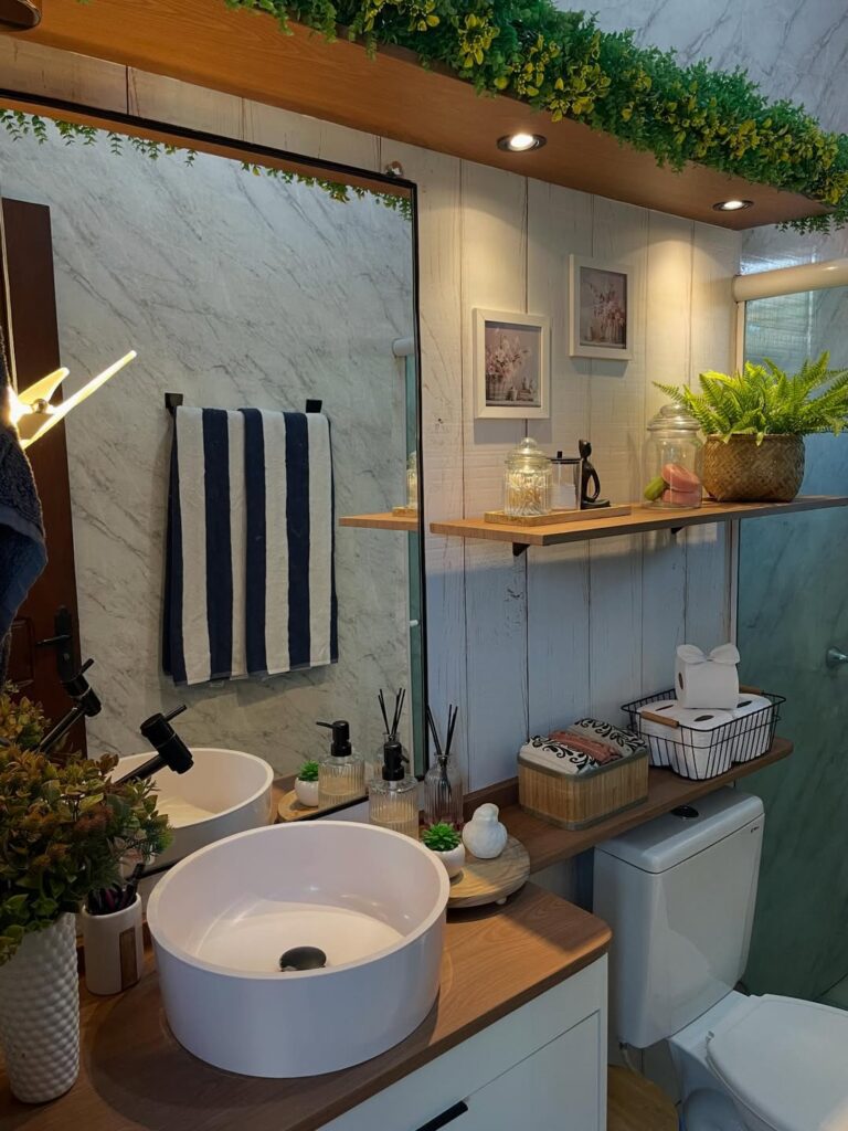 Banheiro com prateleiras de madeira e itens decorativos como quadros, cestos e bandeja