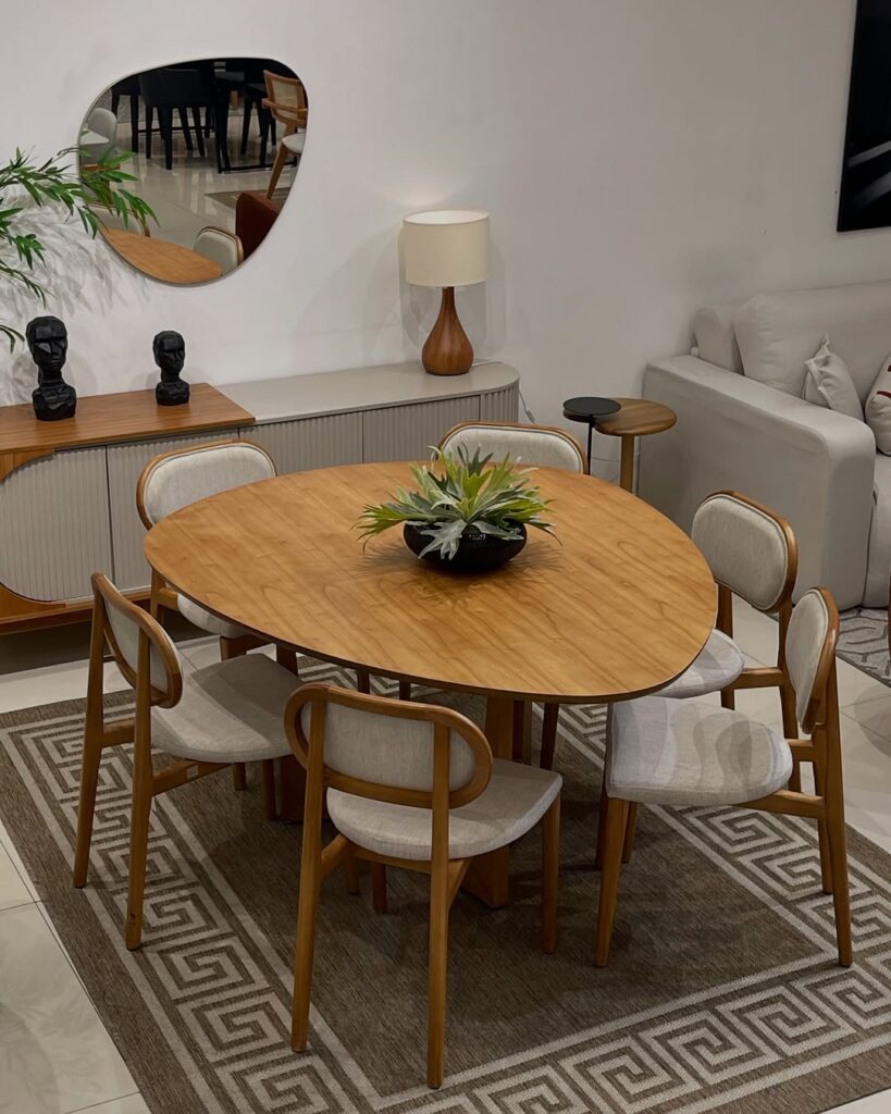 Sala de jantar com mesa de linhas orgânicas de madeira, buffet cinza com madeira e espelho curvo