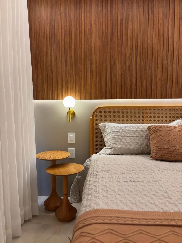 Quarto com cabeceira de palhinha, painel amadeirado e mesinhas ao lado da cama