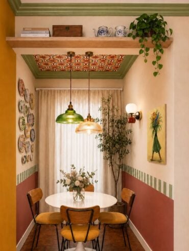 Sala de jantar com mesa redonda, cadeiras com assento amarelo, pendentes coloridos e pratos na parede