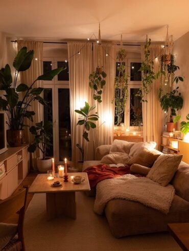 Sala de estar com cortinas, plantas suspensas, sofá com textura e luz baixa