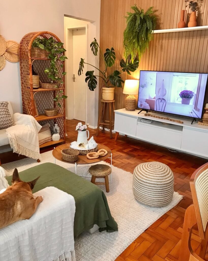Sala de estar com painel ripado, rack branco e pés palitos, estante de vime e plantas