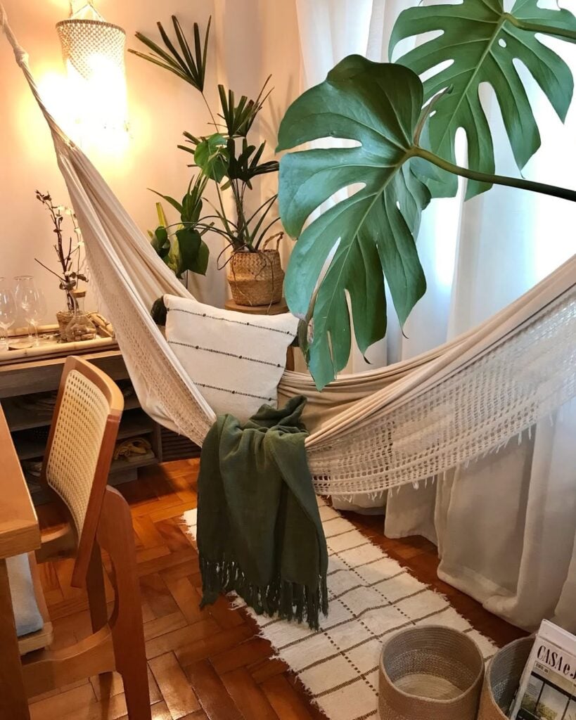 Cantinho dentro de casa com rede, almofadas e planta