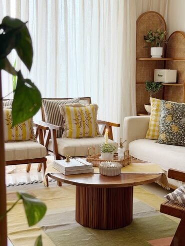 Sala de estar com sofá e poltronas claros, almofadas com flores e amarelo e mesa de centro moderna
