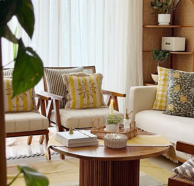 Sala de estar com sofá e poltronas claros, almofadas com flores e amarelo e mesa de centro moderna