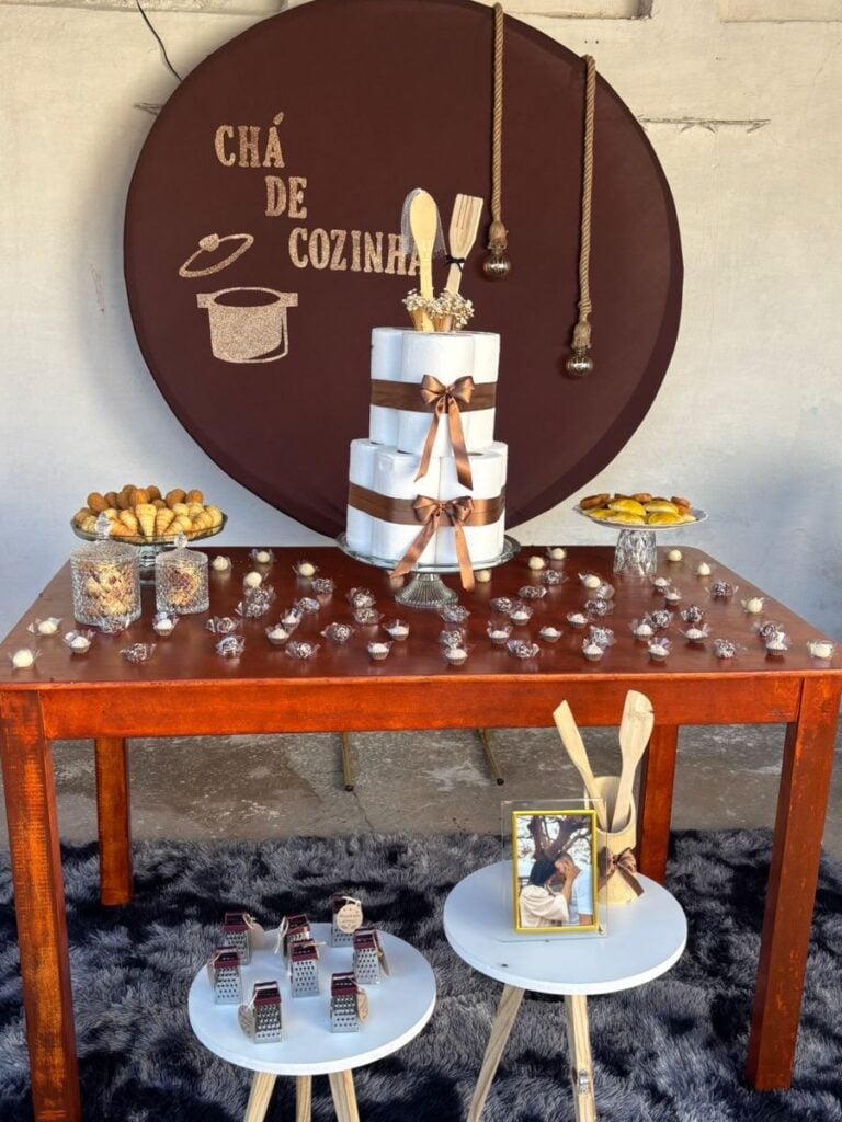 Decoração de chá de cozinha com docinhos na mesa, rolos de toalha de papel agrupados como bolo e utensílios de cozinha