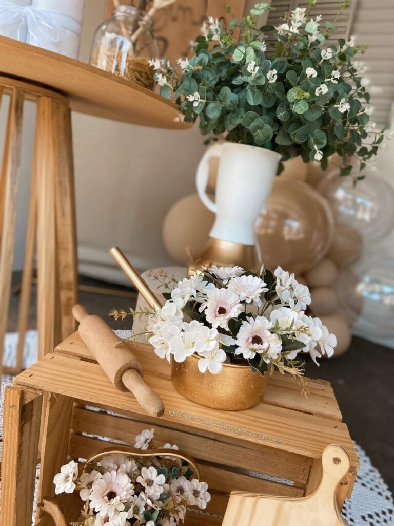Decoração de chá de cozinha com caixote e rolo de madeira, e panela dourada com flores brancas