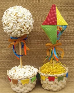 Enfeites de São João para mesa com base de palha e palitos com pipoca e balão de tecidos coloridos