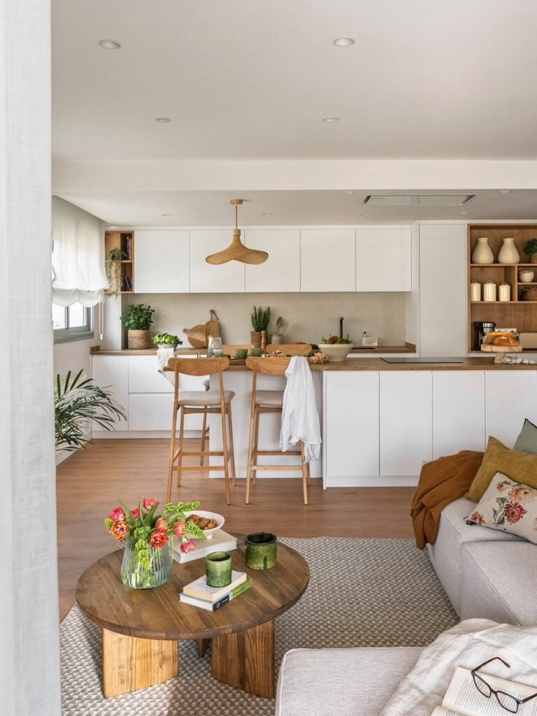 Sala de estar e cozinha integradas com móveis brancos e amadeirados