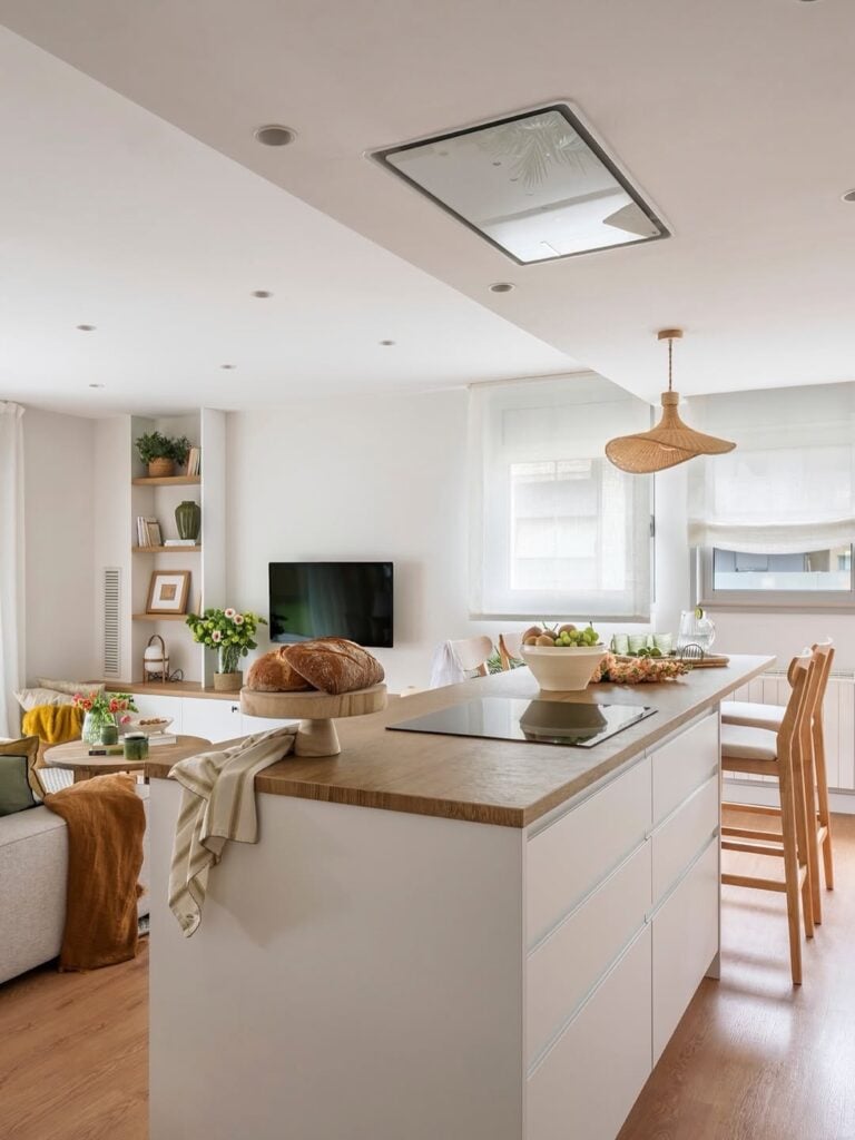 Ilha na cozinha com balcão branco e bancada de madeira