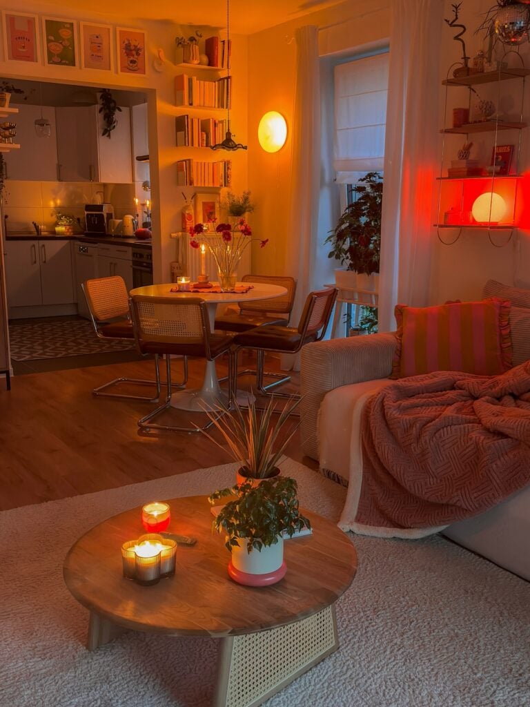 Sala com tapete, sofá com manta, mesa de centro redonda e luminárias de luzes amarelas