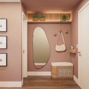 Hall de apartamento com a parede rosa, espelho orgãnico, banco e suporte para bolsas