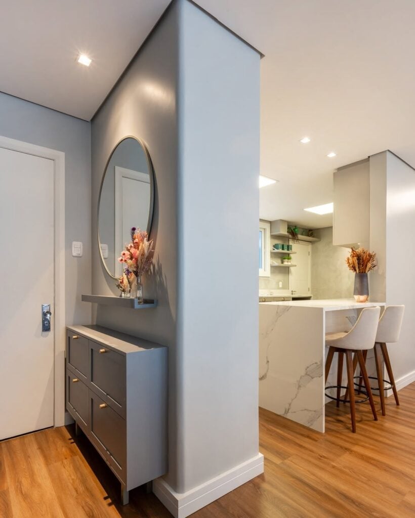 Hall de apartamento com móvel e armazenamento, espelho redondo e prateleira