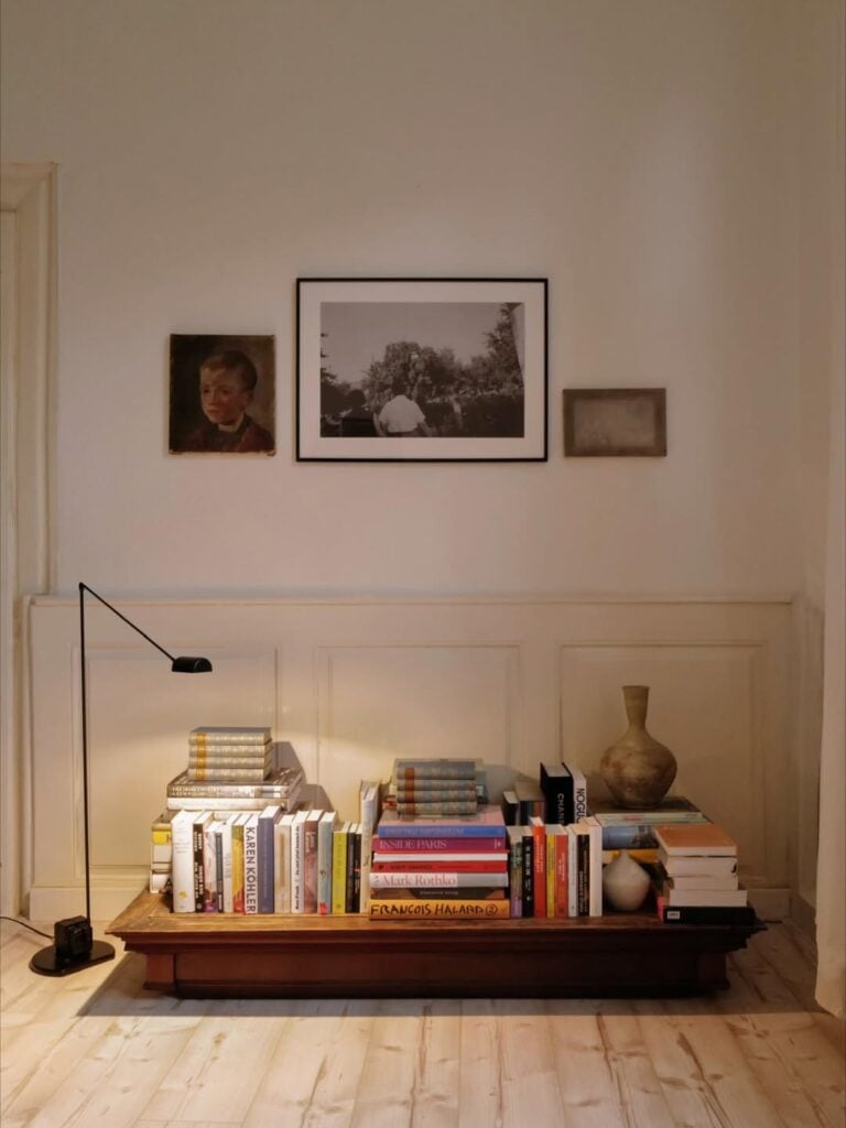 Mesa baixa de maderia com vários livros e luminária de piso ao lado