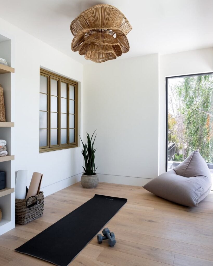 Espaço para yoga com tapete, pufe, halteres e vaso com planta