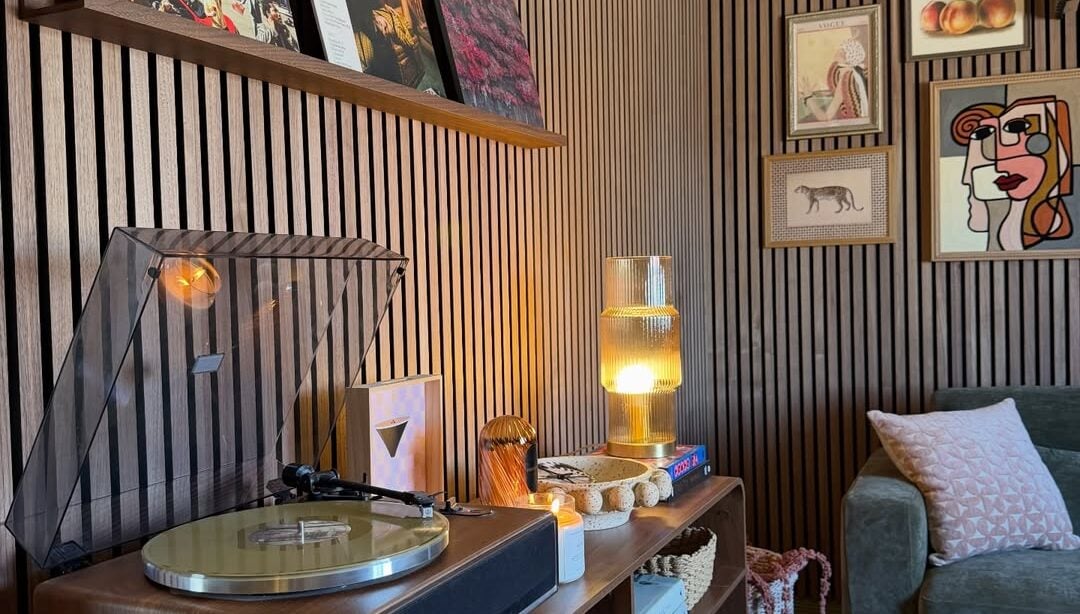 Sala de estar com paineis ripados na parede, prateleira com discos e móvel de madeira com vitrola