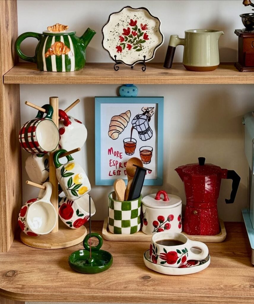 Estante de madeira com cafeteira italiana vermelha, suporte de madeira com canecas em cerâmica com desenhos coloridos