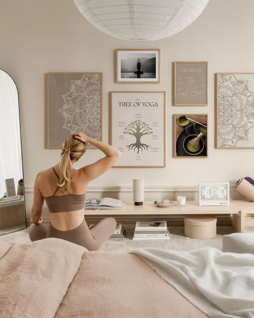 Espaço para Yoga em tons neutros, quadros na parede e mulher se exercitando