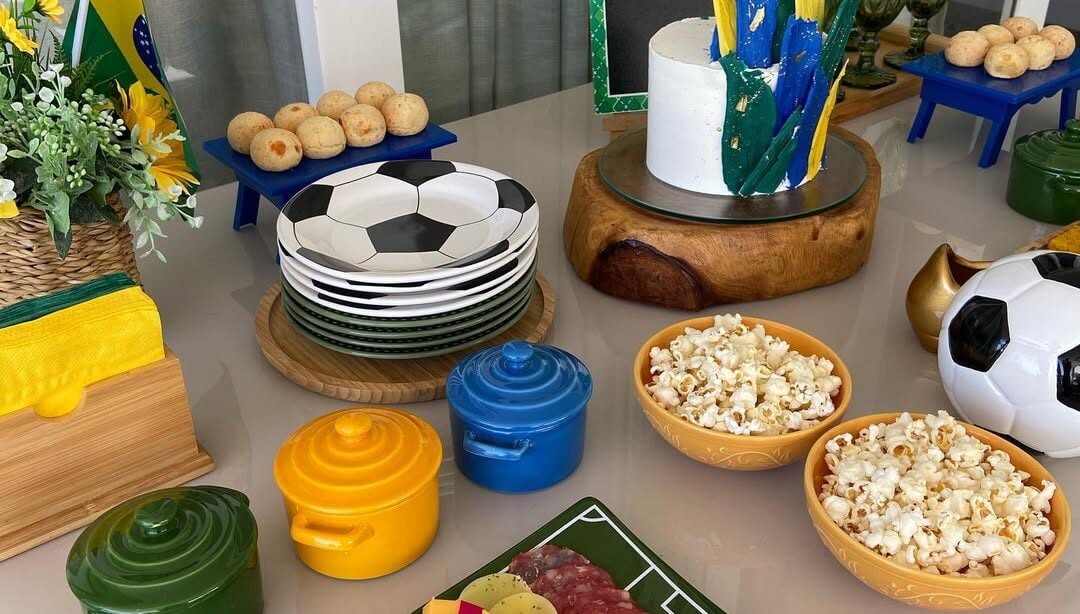 Mesa decorada para Copa, com panelinhas em verde, amarelo e azul, e pratinhos com dezenhos de bola