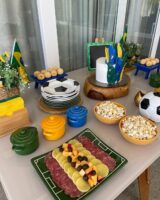 Mesa decorada para Copa, com panelinhas em verde, amarelo e azul, e pratinhos com dezenhos de bola
