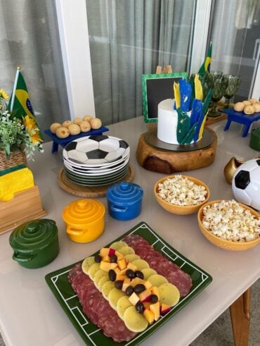 Mesa decorada para Copa, com panelinhas em verde, amarelo e azul, e pratinhos com dezenhos de bola
