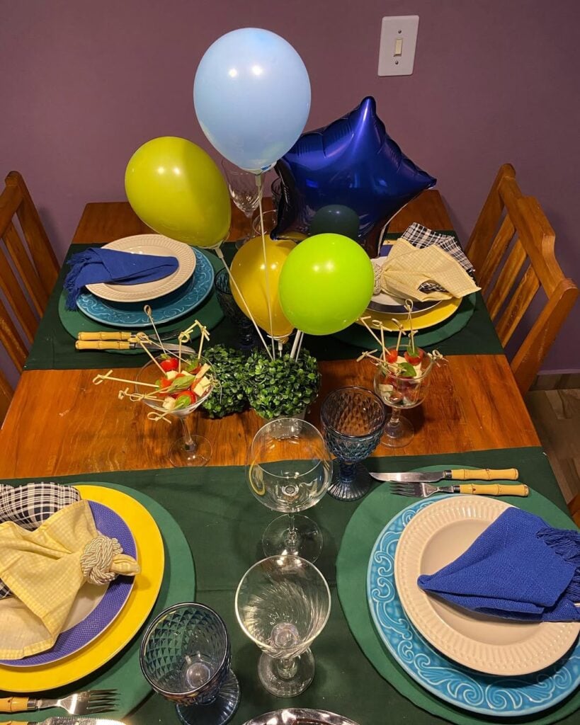 Mesa decorada para Copa com balões em verde, azul e amarelo, e itens de mesa coloridos