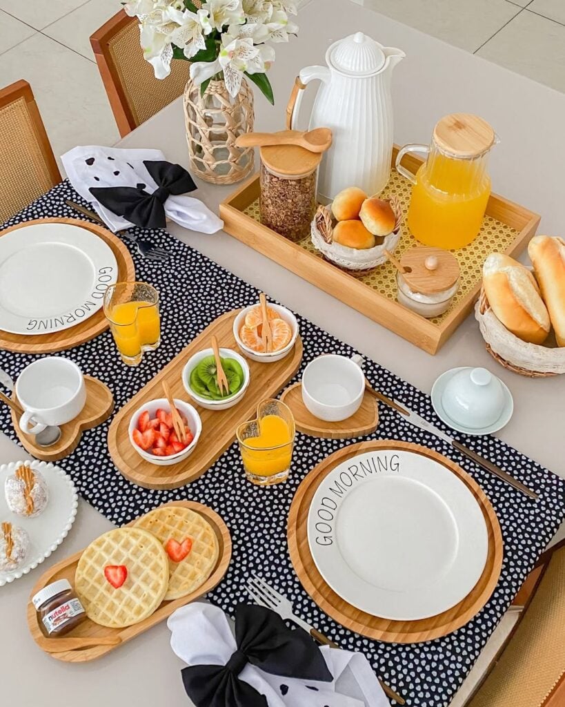 Mesa posta com caminho de mesa preto com branco, itens de bambu, e copos em formato de coração