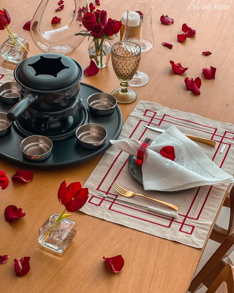 Mesa posta de Dia dos Namorados com aparelho de fondue e pétalas vermelhas