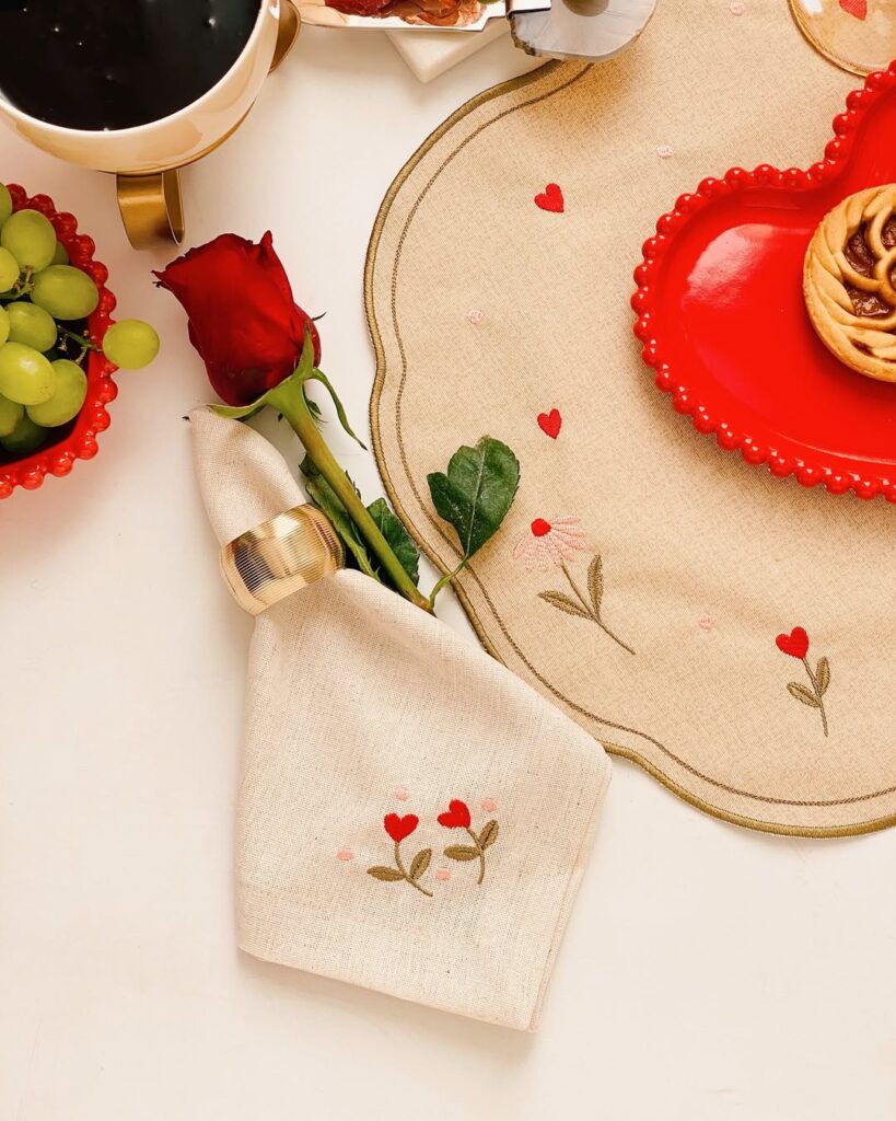 Mesa posta de Dia dos Namorados com jogo americano e guardanapo com bordados de corações, pratinho vermelho e rosa