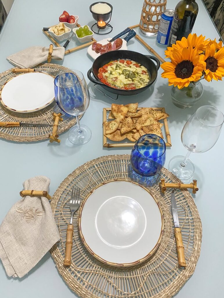 Mesa posta de Dia dos Namorados com sousplats bege, copos azuis e pizza na frigideira