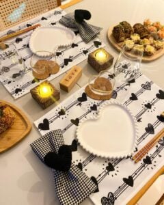 Mesa posta de Dia dos Namorados com jogo americano branco com corações pretos, guardanapos xadrez preto e branco