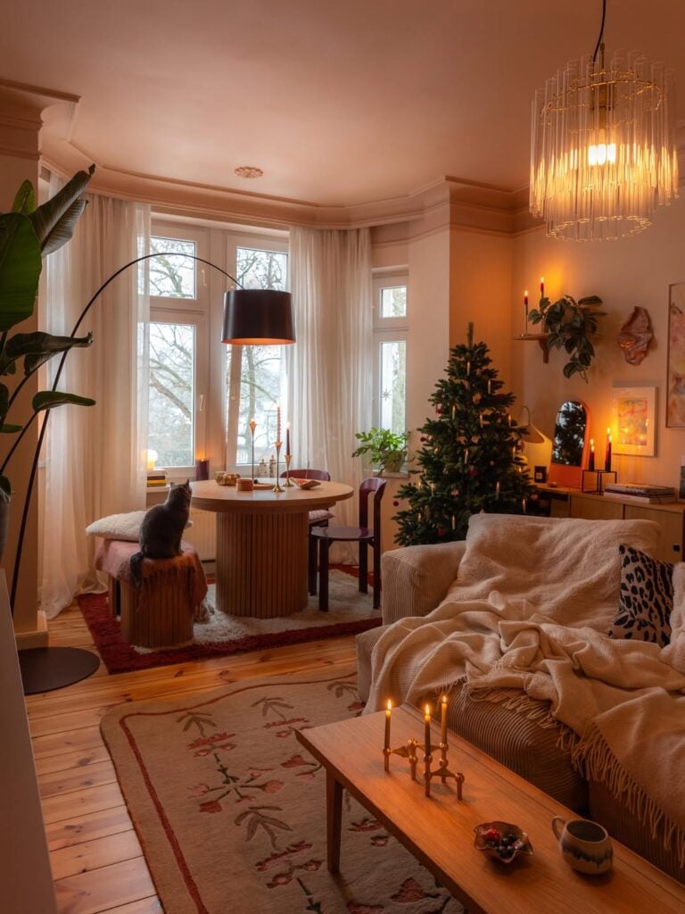 Sala de estar e jantar, sofá com manta, mesa de centro com velas e iluminação quente