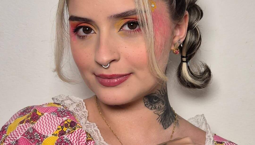 Mulher de pele clara, com maquiagem colorida e penteado de São João