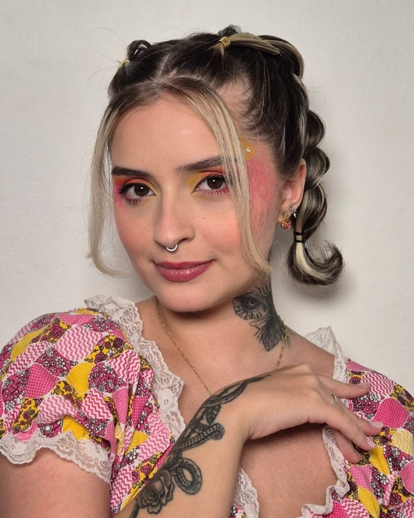 Mulher de pele clara, com maquiagem colorida e penteado de São João 