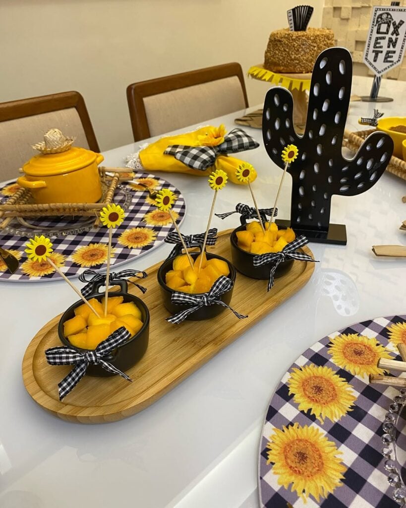 Mesa posta junina em amarelo e preto com panelinhas com guloseima amarela