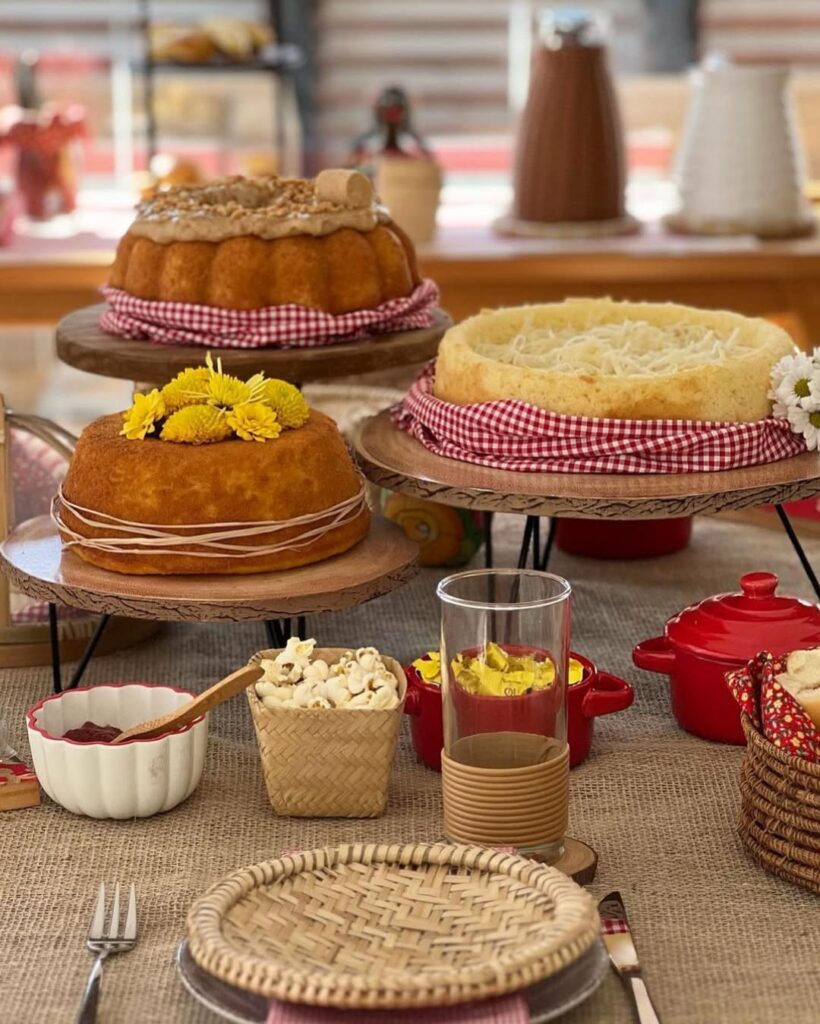 Mesa de São João com bolos variados, pipoca e paçoca