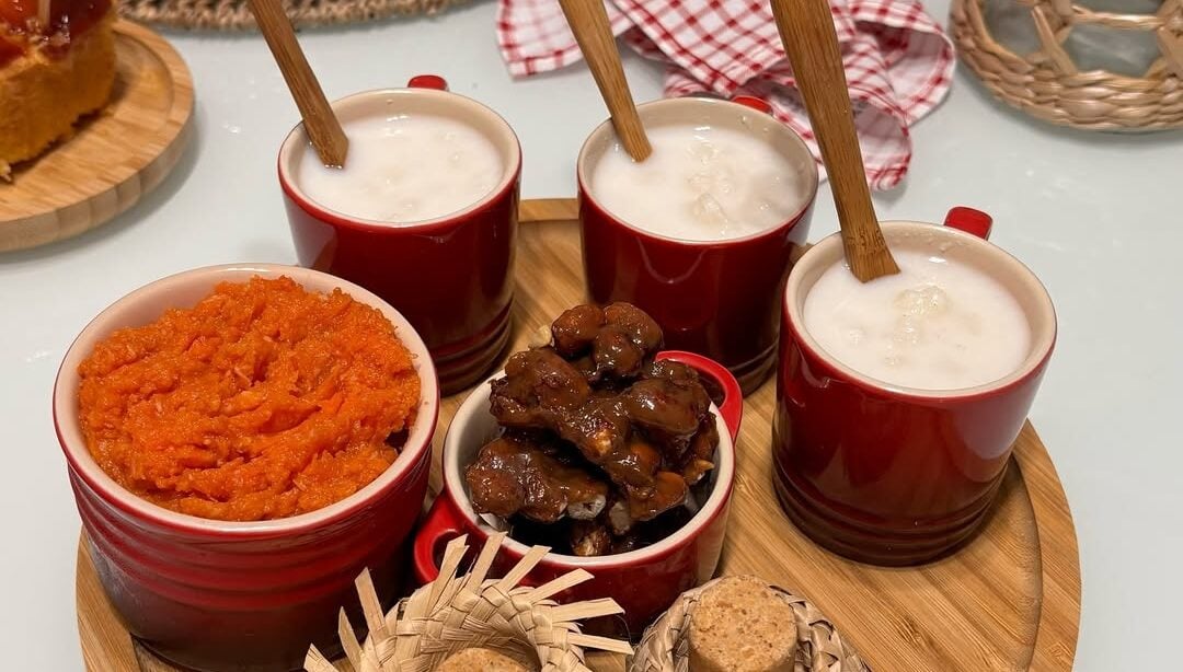 Bandeja de bambu com canecas vermelhas com canjica, pé de moleque e doce de abóbora