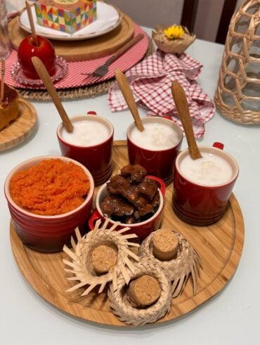 Bandeja de bambu com canecas vermelhas com canjica, pé de moleque e doce de abóbora