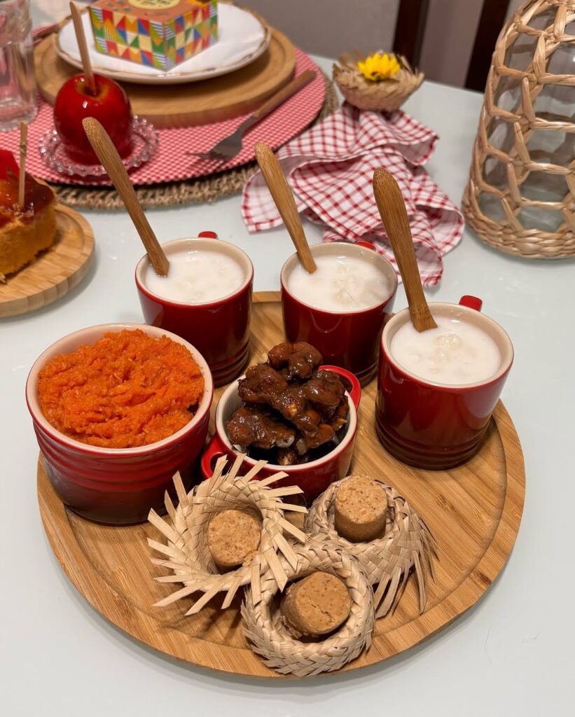 Bandeja de bambu com canecas vermelhas com canjica, pé de moleque e doce de abóbora