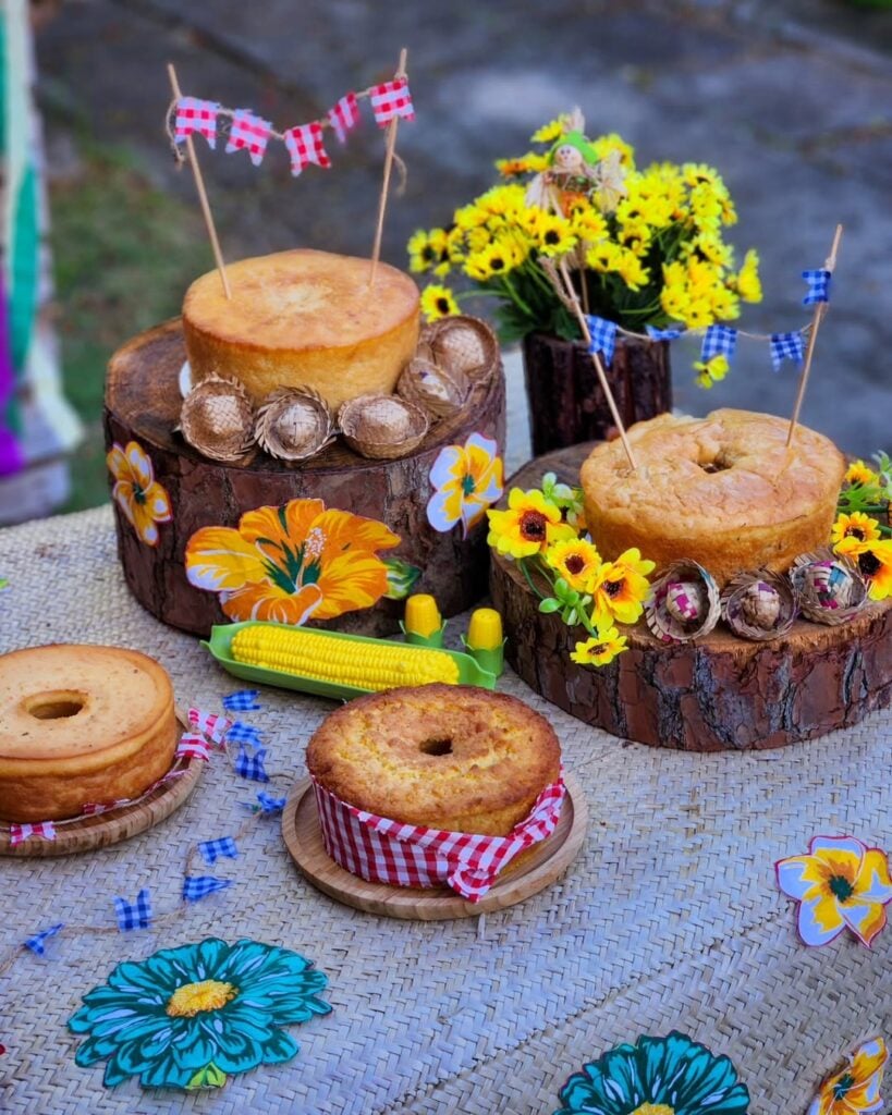 Mesa junina com bolos e flores amarelas
