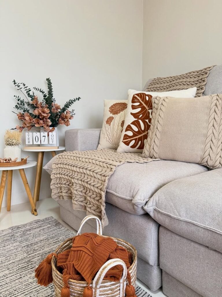 Sala com sofá neutro aconchegante,, almofadas e manta com texturas e tons terrosos