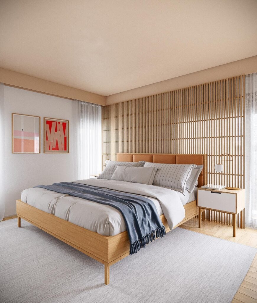 Quarto de casal com cama, mesa de cabeceira e manta azul, com tapete grande no chão e quadros na parede